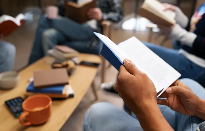 personnes qui lisent un livre autour d'une table