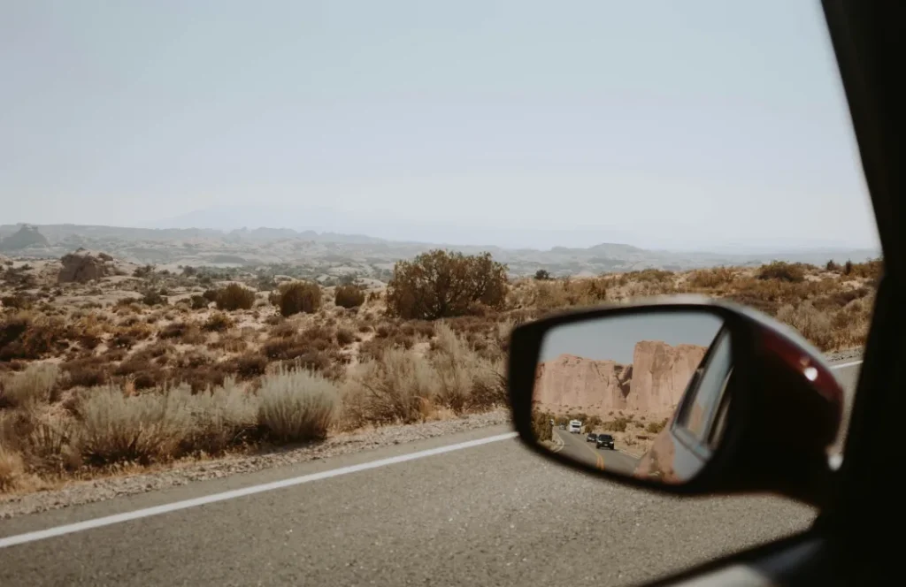 une voiture d'où l'on regarde le paysage dans le rétroviseur.